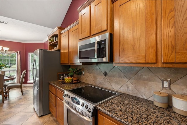 kitchen with brown cabinets, a chandelier, dark stone countertops, tasteful backsplash, and appliances with stainless steel finishes