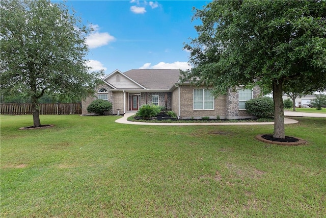 ranch-style home with a front yard, brick siding, and fence