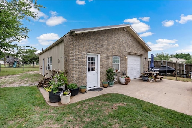 rear view of house featuring driveway, a lawn, fence, brick siding, and a garage