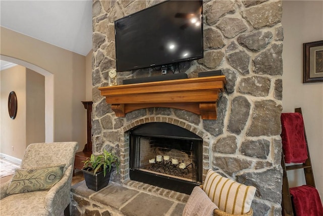 interior space featuring arched walkways and a stone fireplace
