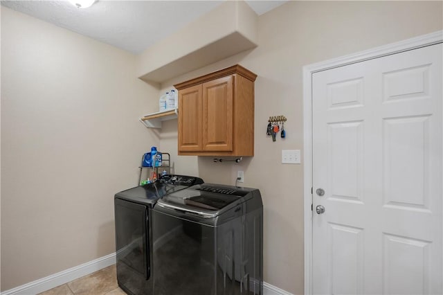 laundry area featuring light tile patterned flooring, cabinet space, baseboards, and washer and clothes dryer