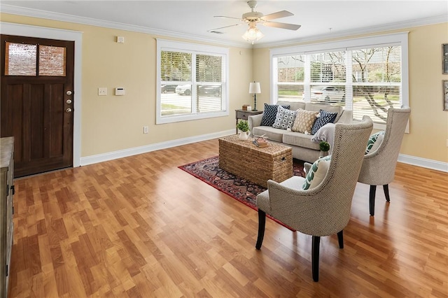 living room with light wood-style flooring, baseboards, and ornamental molding