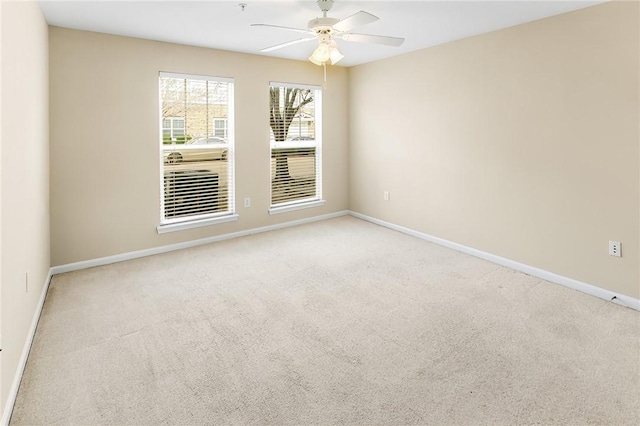 carpeted empty room featuring baseboards and a ceiling fan