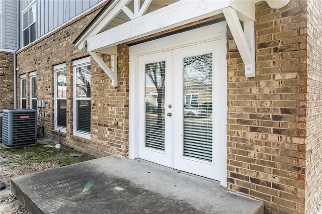 property entrance featuring french doors, brick siding, and central AC