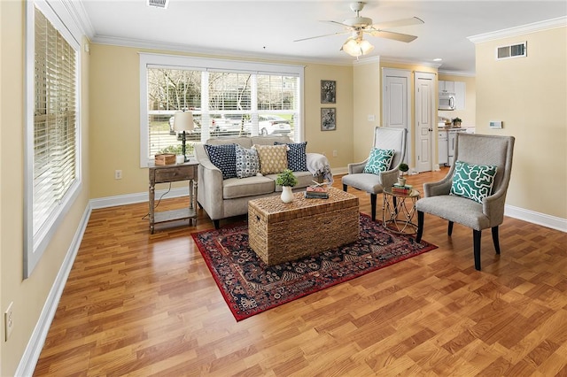 living room with crown molding, light wood-style floors, and visible vents