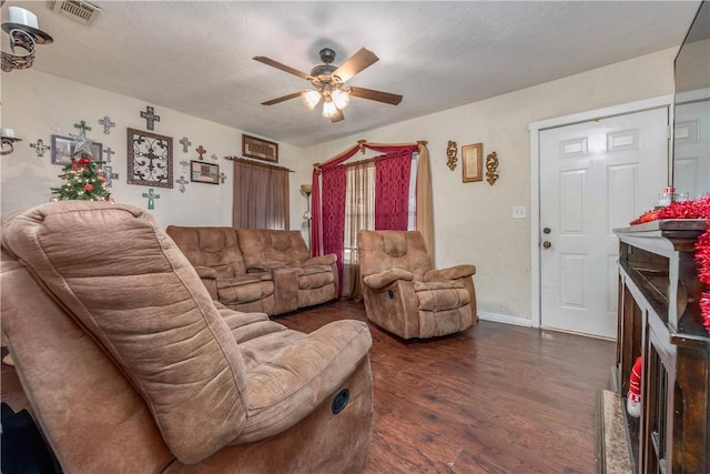 living area with a textured ceiling, visible vents, baseboards, a ceiling fan, and dark wood-style floors