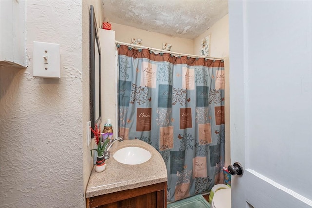 full bathroom with a textured ceiling, a textured wall, a shower with shower curtain, and vanity