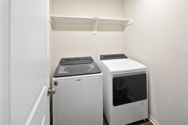 clothes washing area with washer and dryer and dark hardwood / wood-style flooring