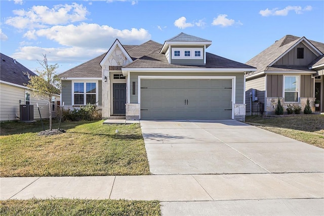 view of front of property with central air condition unit, a front yard, and a garage