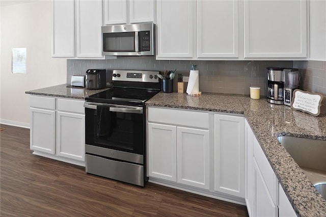 kitchen featuring white cabinetry, dark wood-type flooring, dark stone counters, and appliances with stainless steel finishes