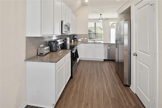 kitchen with stainless steel appliances, sink, white cabinetry, stone countertops, and backsplash