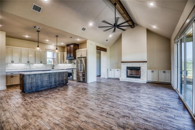 kitchen featuring a fireplace, wood-type flooring, premium appliances, hanging light fixtures, and a center island