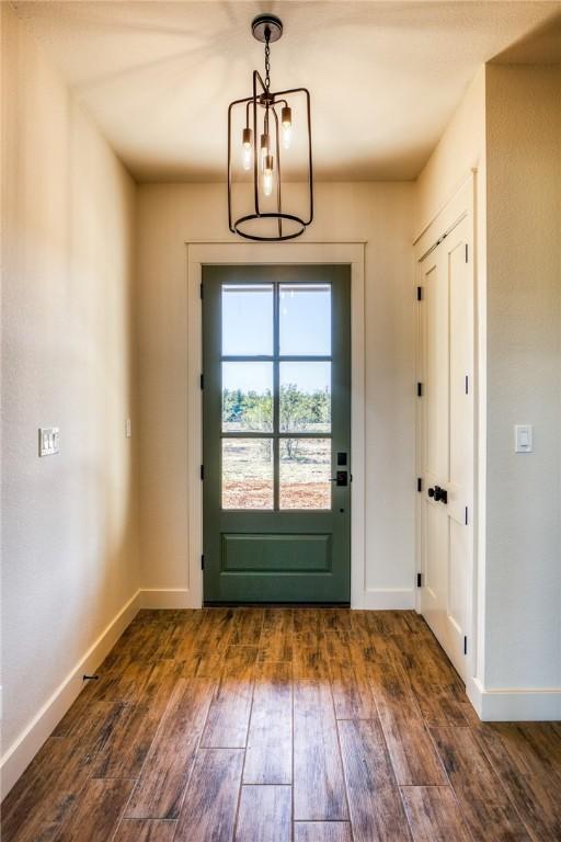 doorway to outside with dark wood-type flooring and a chandelier