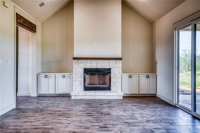 unfurnished living room featuring a fireplace, vaulted ceiling, and a wealth of natural light