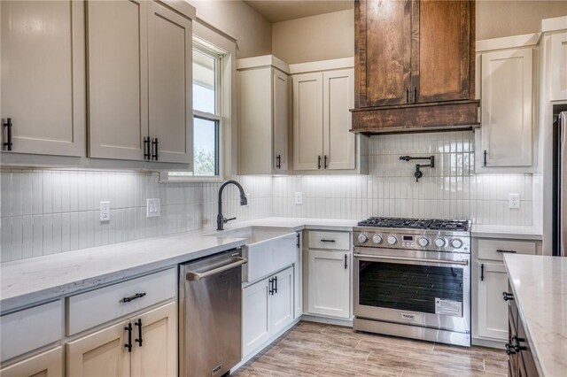 kitchen with appliances with stainless steel finishes, sink, backsplash, and light stone counters