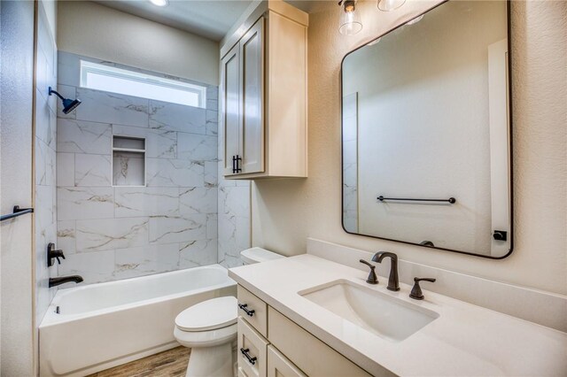 full bathroom featuring tiled shower / bath, vanity, toilet, and hardwood / wood-style floors