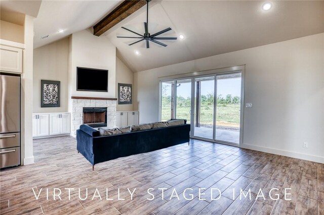 living room with ceiling fan, a stone fireplace, high vaulted ceiling, and beam ceiling