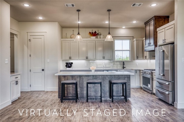 kitchen with a breakfast bar, tasteful backsplash, a center island, hanging light fixtures, and high quality appliances