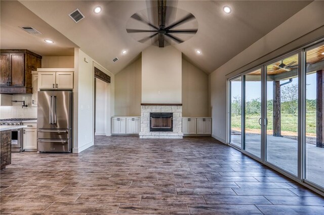 unfurnished living room with a stone fireplace, high vaulted ceiling, and ceiling fan