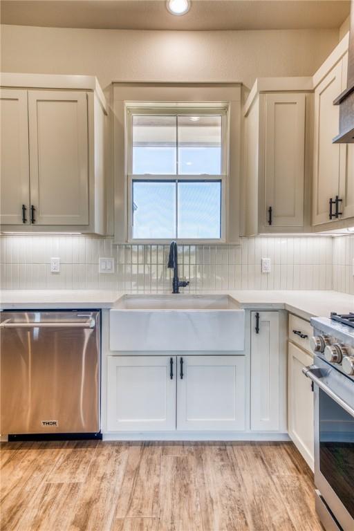 kitchen featuring tasteful backsplash, stainless steel appliances, sink, and light hardwood / wood-style flooring