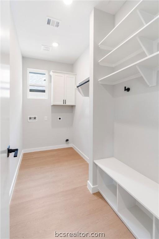 laundry area featuring washer hookup, electric dryer hookup, cabinets, and light wood-type flooring