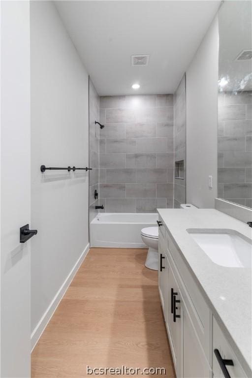 full bathroom featuring toilet, hardwood / wood-style floors, vanity, and tiled shower / bath