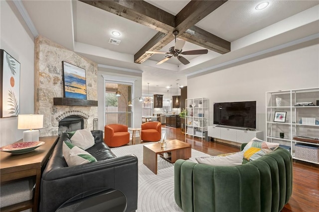 living area featuring dark wood-style flooring, beam ceiling, a fireplace, visible vents, and coffered ceiling