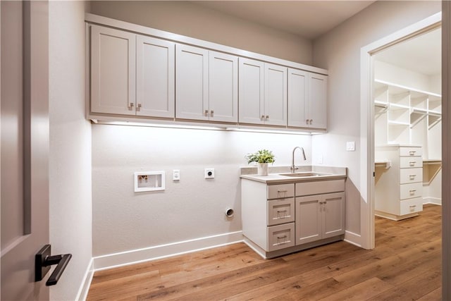 laundry area with sink, electric dryer hookup, cabinets, washer hookup, and light wood-type flooring