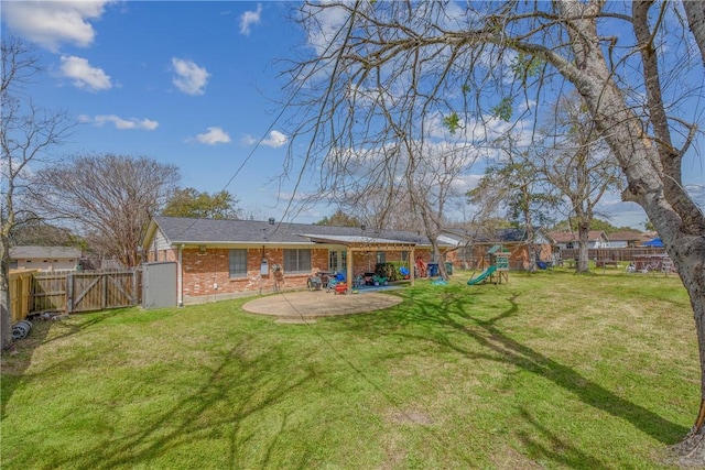 rear view of property with a yard, a patio, brick siding, and a playground