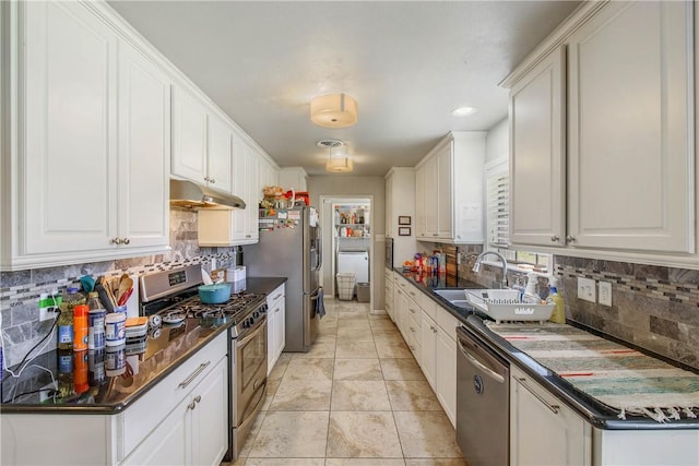 kitchen featuring stainless steel appliances, dark countertops, a sink, and under cabinet range hood