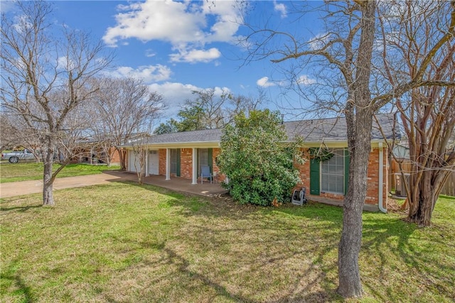 single story home featuring driveway, a front yard, a garage, and brick siding