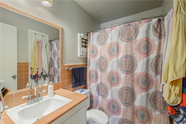 full bath with toilet, a shower with shower curtain, tile walls, and vanity