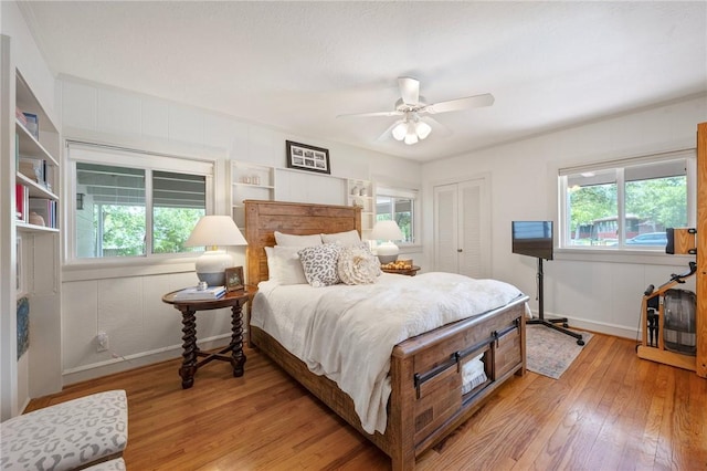 bedroom featuring a closet, multiple windows, baseboards, and light wood-style floors