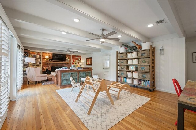 dining area featuring a brick fireplace, light wood finished floors, visible vents, and ceiling fan