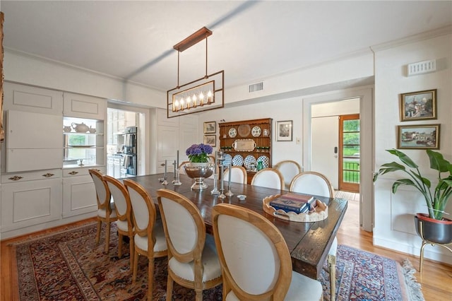 dining room with visible vents, ornamental molding, a notable chandelier, and light wood-style floors