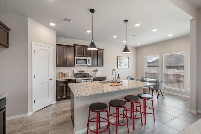 5308 Lyle Pl, Bryan, TX 77807 - kitchen featuring stainless steel appliances, a sink, baseboards, dark brown cabinets, and recessed lighting