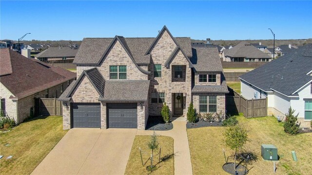 view of front of home with concrete driveway, fence, brick siding, and a front lawn