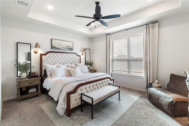 carpeted bedroom featuring a tray ceiling and ceiling fan