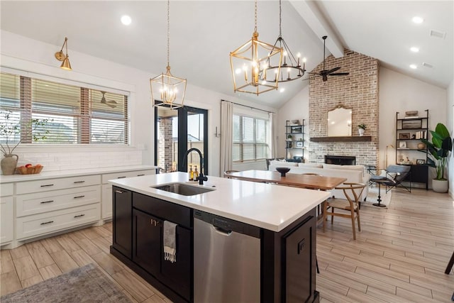 kitchen with dishwasher, white cabinets, decorative light fixtures, a fireplace, and sink