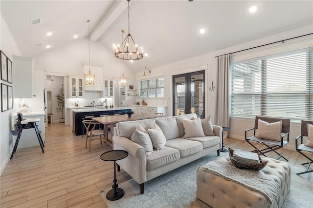 living room featuring beamed ceiling, light wood-type flooring, high vaulted ceiling, and an inviting chandelier