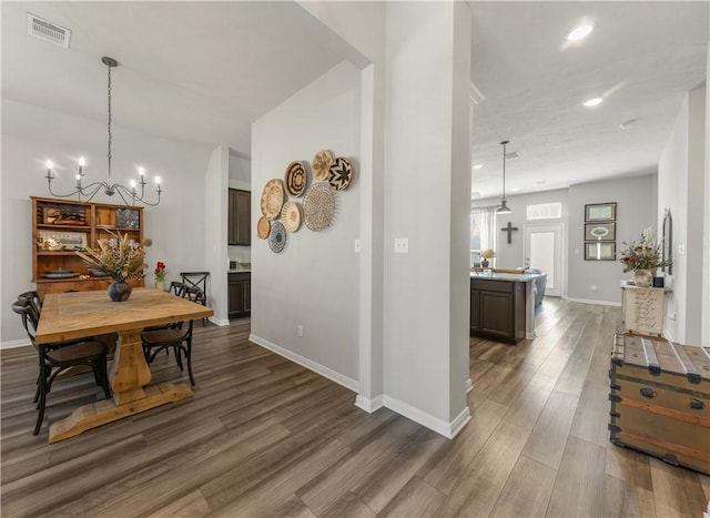 dining space with baseboards, visible vents, a chandelier, and dark wood-type flooring