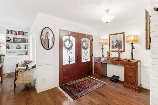 foyer with dark wood-type flooring, a textured ceiling, and french doors