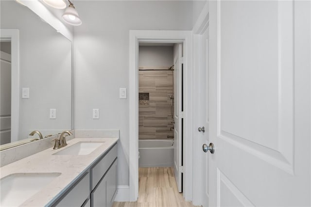 bathroom featuring wood-type flooring, vanity, and tiled shower / bath combo