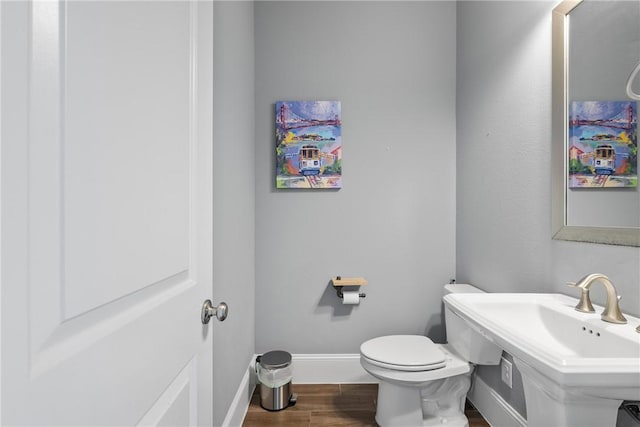 bathroom featuring wood-type flooring, toilet, and sink