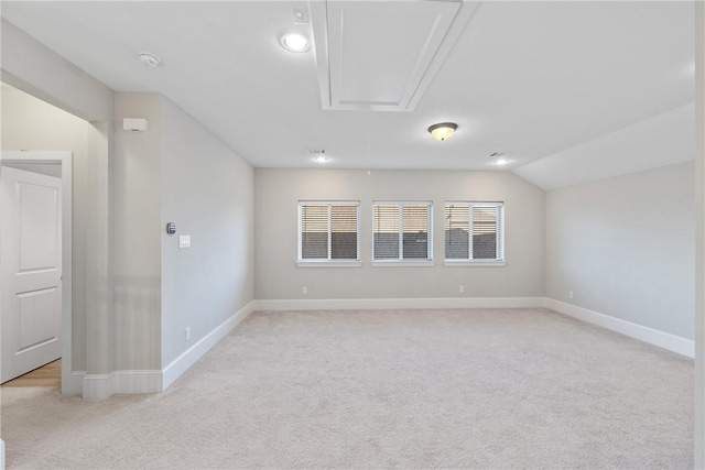 unfurnished room with light colored carpet and vaulted ceiling