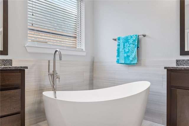 bathroom with a washtub, vanity, and tile walls