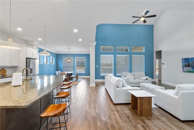 living room featuring ceiling fan, light hardwood / wood-style floors, and a towering ceiling