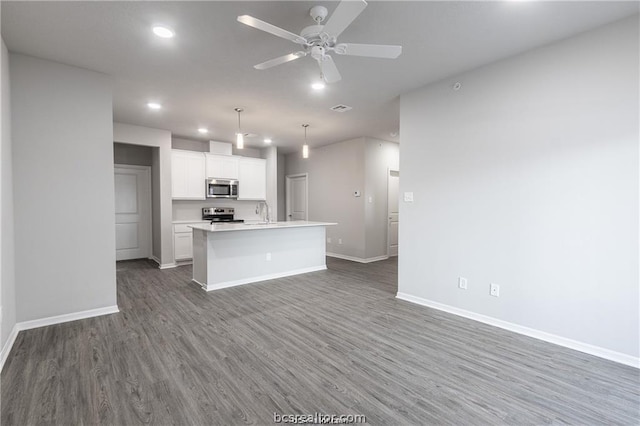 kitchen with dark hardwood / wood-style flooring, stainless steel appliances, a center island with sink, white cabinets, and hanging light fixtures