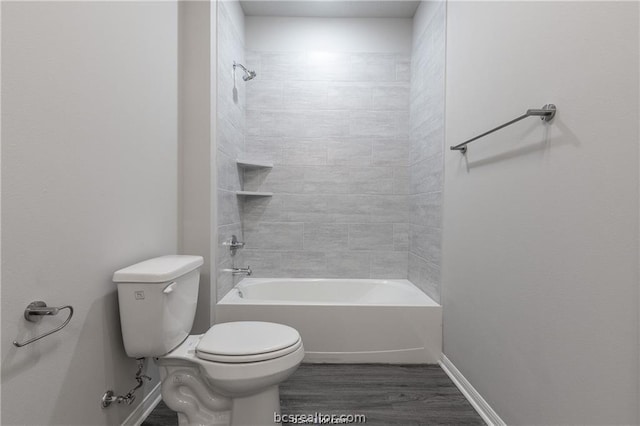 bathroom with tiled shower / bath combo, toilet, and wood-type flooring