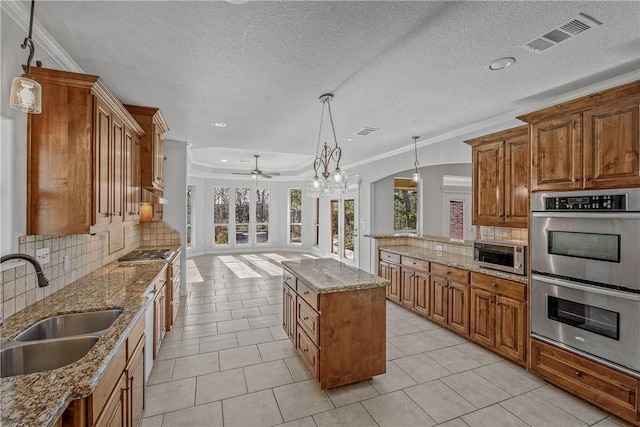 kitchen with decorative light fixtures, a center island, sink, and appliances with stainless steel finishes